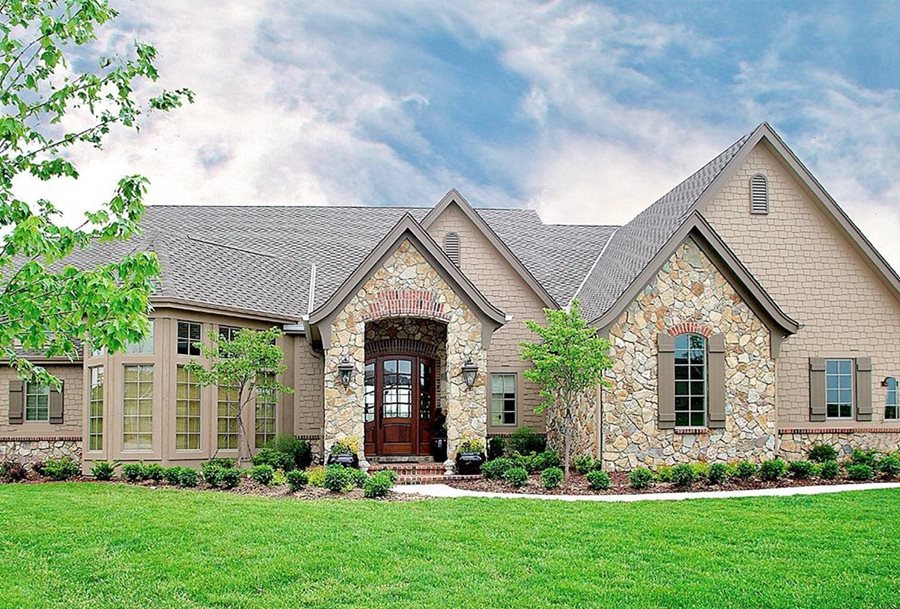 A french country house with shake siding and rustic cut brown stone.