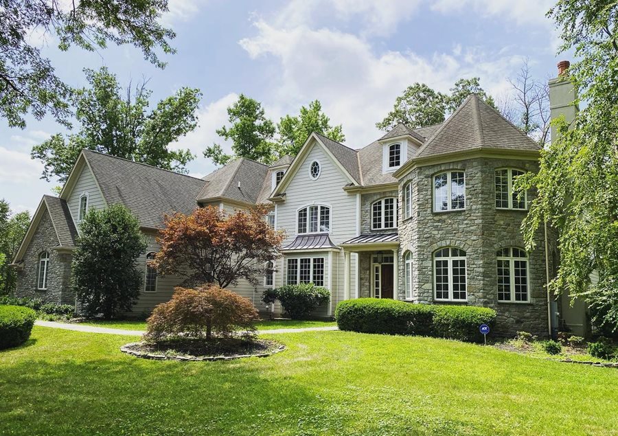 A two-story house in a neutral color palette with light cream siding and gray-toned stone.