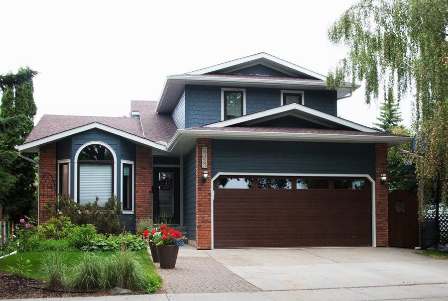 A house with dark blue plank siding with red brick accents.