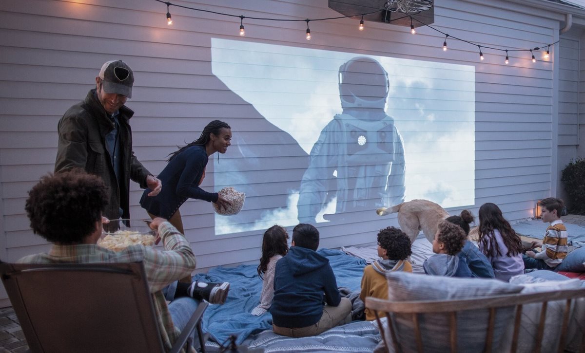 A family hosts a community movie night outdoors while projecting onto Hardie Plank siding.